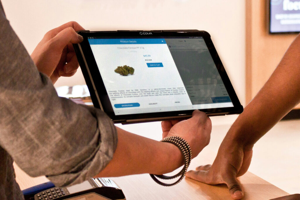 Dispensary employee showing product information on a tablet at checkout