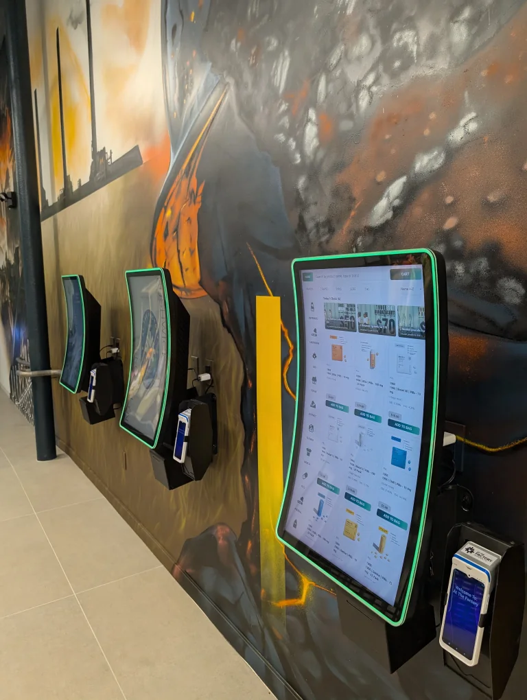 Three wall-mounted Giosk 32CW kiosks installed along a feature wall at At The Factory Cannabis Co. in Bushwick, Brooklyn